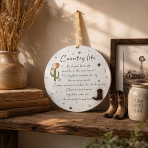 Country Life hanging plaque displayed on a rustic wooden shelf with vintage books, dried wheat, and farmhouse décor accents.