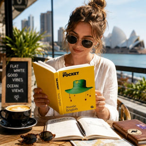 Traveler reading Pocket Aussie English at an outdoor Australian café with coffee and waterfront views