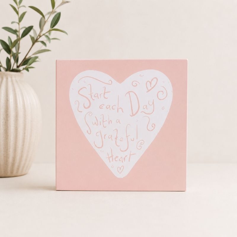 Pink canvas with a white heart-shaped quote "Start each day with a grateful heart" on a light background