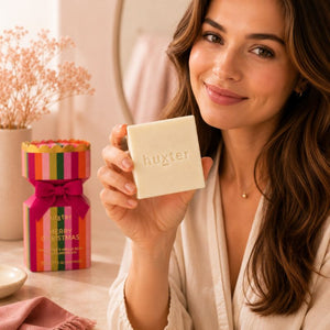 Woman holding Huxter Pink Pepper & Vanilla Bean Body Cleansing Bar with festive gift box