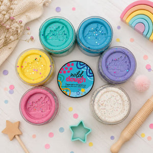 Colorful dough sets with containers and tools on a light surface.
