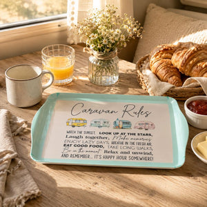 A Caravan Bamboo Melamine Serving Tray with rounded corners sits on a wooden table in a breakfast setting. The tray has a pale aqua border and a white center printed with the phrase 'Caravan Rules' in script, plus small illustrated campers and a short poem.