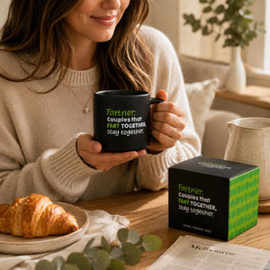 A woman in a cream knit sweater holds a Cheeky Fart Mug
with the printed phrase 'Fartner: Couples that FART TOGETHER, stay together.' in green and white.