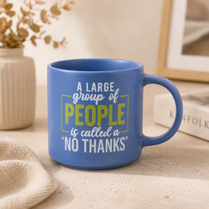 A blue Cheeky No Thanks Mug with a humorous quote printed on it, styled on a light beige tabletop with a neutral background.