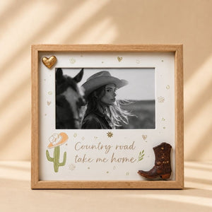 Framed picture Country road take me home with a woman in a cowboy hat, horse, and 'Country road take me home' text on a beige background.