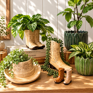 Tan ceramic cowboy boot and hat planters styled with lush green plants and Western-inspired home décor on a wooden surface.