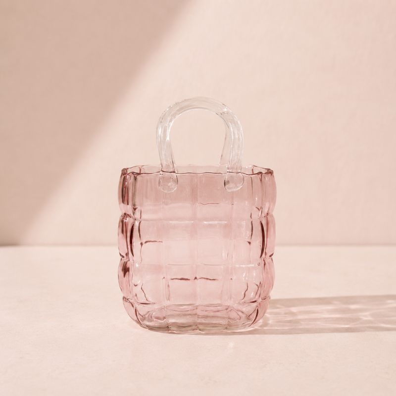 Pink glass handbag with clear handle on a light pink background