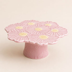 Pink ceramic cake stand with floral design on a beige background