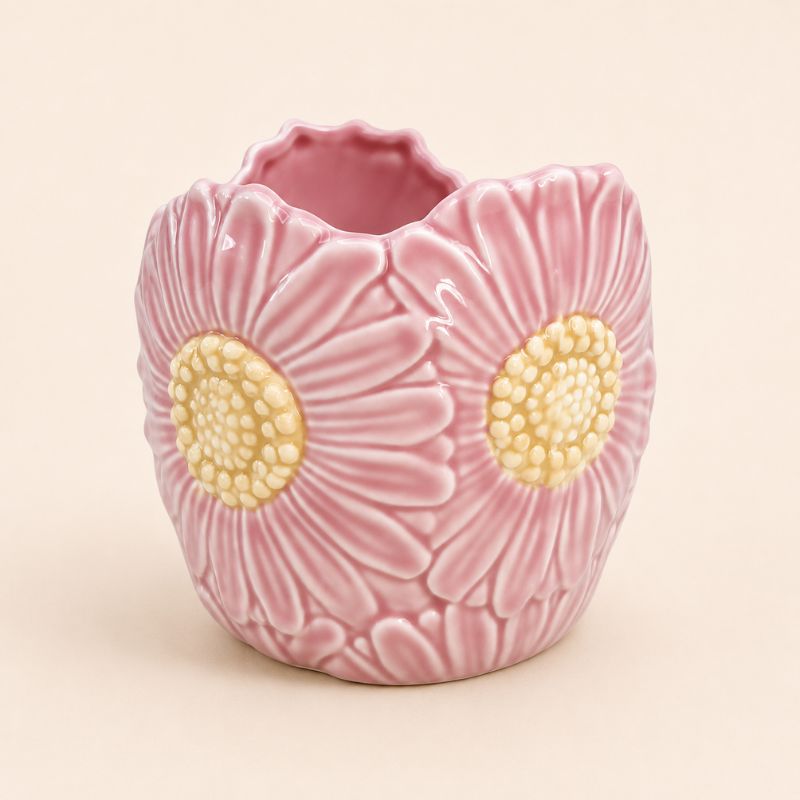 Pink ceramic vase with floral design on a beige background