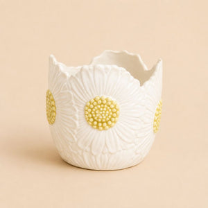White ceramic planter with yellow floral designs on a beige background