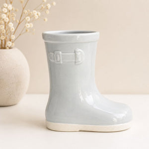 Light blue ceramic boot with buckle details on a beige background