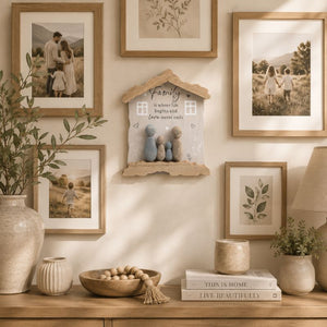 Family hanging plaque nestled wall art and framed photos on a neutral wall.