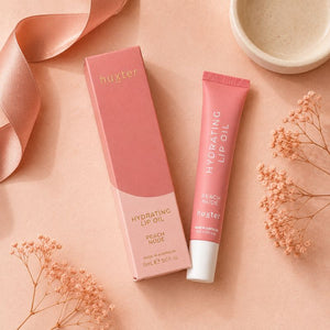 Huxter Peach Nude Hydrating Lip Oil tube and box in overhead blush flat lay