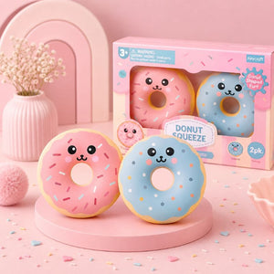 Two donut-shaped toys with a packaging box on a pink background