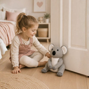 Child holding a plush koala toy door stopper in a cozy room.