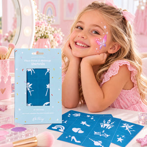 Smiling young girl with butterfly face paint beside Oh Flossy reusable face paint stencils and blue stencil sheets at a pink vanity.