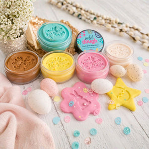 Colorful wild dough in small containers with decorative tools on a light wooden surface.