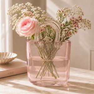 Pink glass vase with flowers on a table