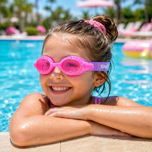 Young girl wearing Rock Candy Pink Swim Goggles while enjoying a sunny day at the swimming pool, showcasing the comfortable fit and playful candy-inspired design.