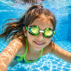Young girl swimming underwater wearing Rattlesnake Royal Serpent swim goggles in a clear blue pool