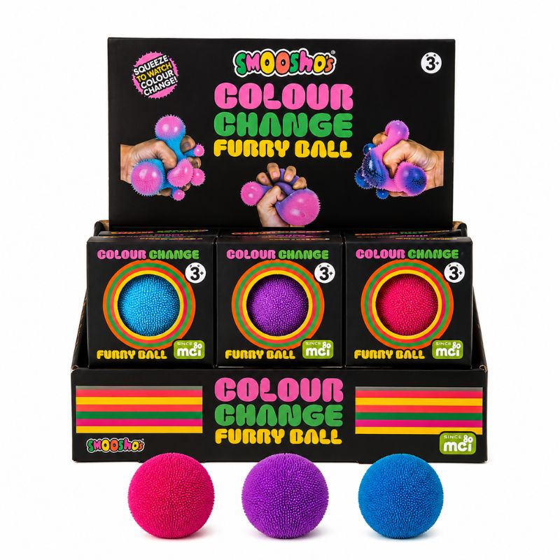 A retail display box of Moodys Colour Change Furry Ball toys, showing three individual balls in pink, purple, and blue, with the black display packaging behind them on a white background.