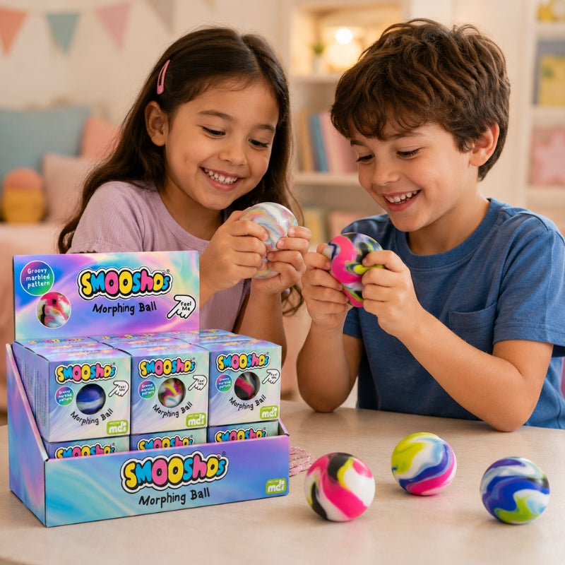 Two children smiling and playing with colorful Swiggy Smoosh Morphing Balls in a bright indoor setting, with a display box of Swiggy Smoosh Morphing Balls on the table.