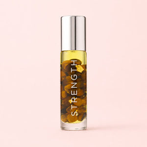 Bottle of 'STRENGTH' oil with a metallic cap on a pink background