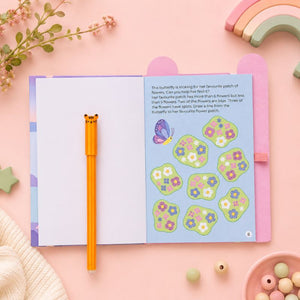 Busy Whiz Unicorn Open book with butterfly illustration and flower stickers on a pink surface with toys and plants. - Loveshack Giftware