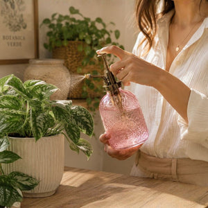 Person holding a pink glass bottle with a plant in the foreground-Loveshack Giftware