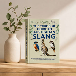The True Blue Guide to Australian Slang displayed on a wooden table beside a ceramic vase with greenery