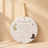 Country Life round hanging plaque with cowboy boot accent and cactus illustration on a warm beige background.