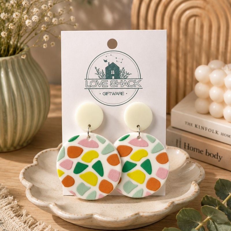 Handmade Aztec dangle earrings with colorful geometric polymer clay design on neutral stud tops.