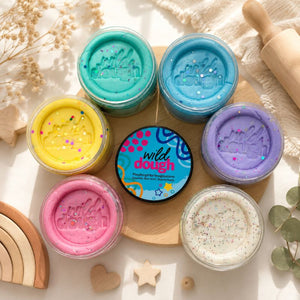 Assorted jars of wild dough on a wooden board with decorative elements.
