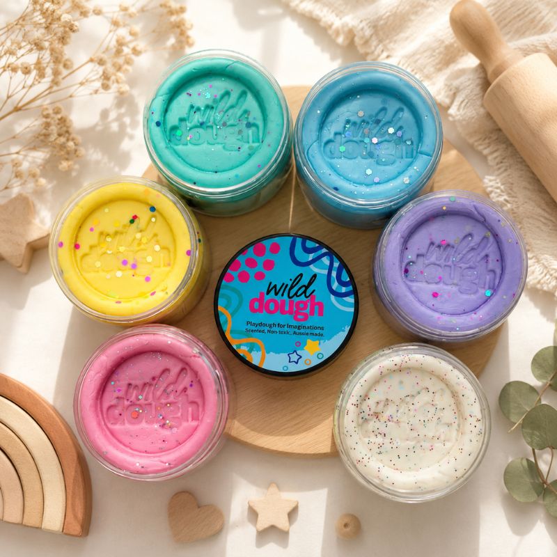 Assorted jars of wild dough on a wooden board with decorative elements.