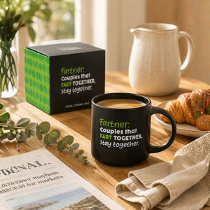 ACheeky Fart Mug
filled with coffee sits on a wooden table, printed with the phrase 'Fartner: Couples that FART TOGETHER, stay together.' in green and white text.