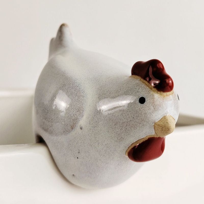 A small ceramic chicken figurine with a speckled light gray body, dark red comb and wattle, and a beige beak, shown close up against a white background.-Chicken Pot Hanger White 6cm