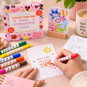 Adult affirmation colouring kit with wooden stand, markers and uncoloured cards on a pink background