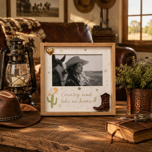 Framed photo Country Road Take Me Home of a woman and horse with decorative elements on a wooden table.
