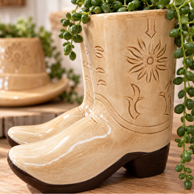 Close-up of tan ceramic cowboy boot planter showing glossy glaze and embossed floral detailing.