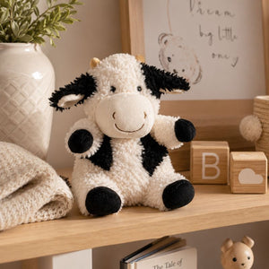 Curly Cow Soft Toy White & Black 18cm displayed on a wooden nursery shelf with baby décor by Love Shack Giftware