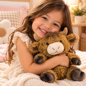 Child cuddling a brown Curly Highland Cow soft toy