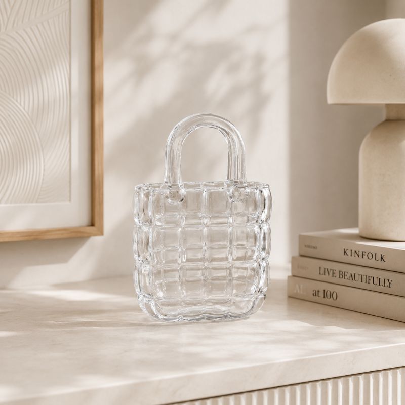 Clear glass bag on a light surface with books and a lamp in the background