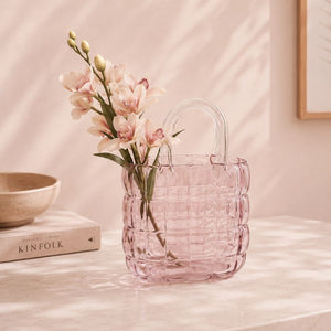 Pink woven vase with flowers on a light surface