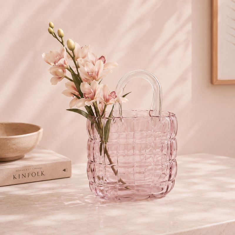 Pink woven vase with flowers on a light surface
