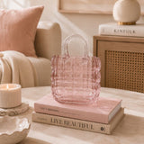 Pink textured handbag on books with a cozy living room background