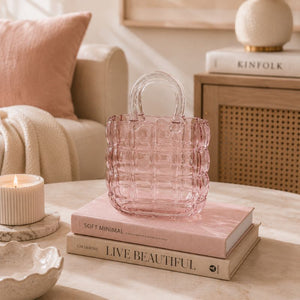 Pink textured handbag on books with a cozy living room background