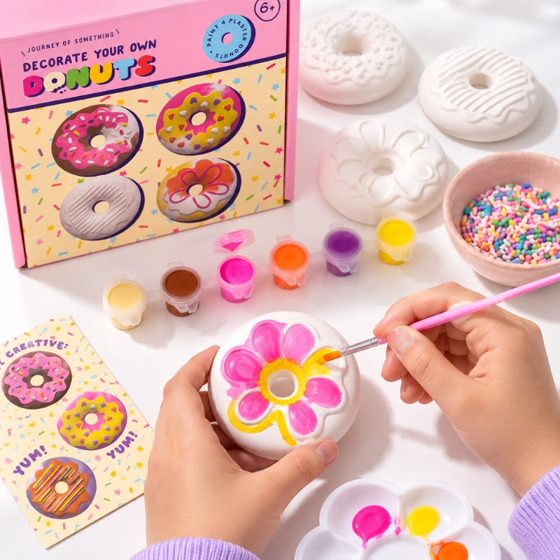 Child decorating a plaster donut with paints, brushes and colourful sprinkles