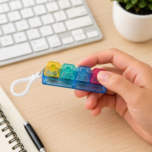 Fidget Fingers Keyboard Click Keychain held by a hand on a desk.