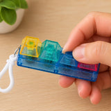 Fidget Fingers Keyboard Click Keychain held by a hand on a wooden surface.