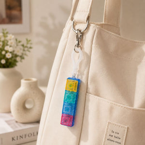 Fidget Fingers Keyboard Click Keychain attached to a beige bag with a blurred indoor background